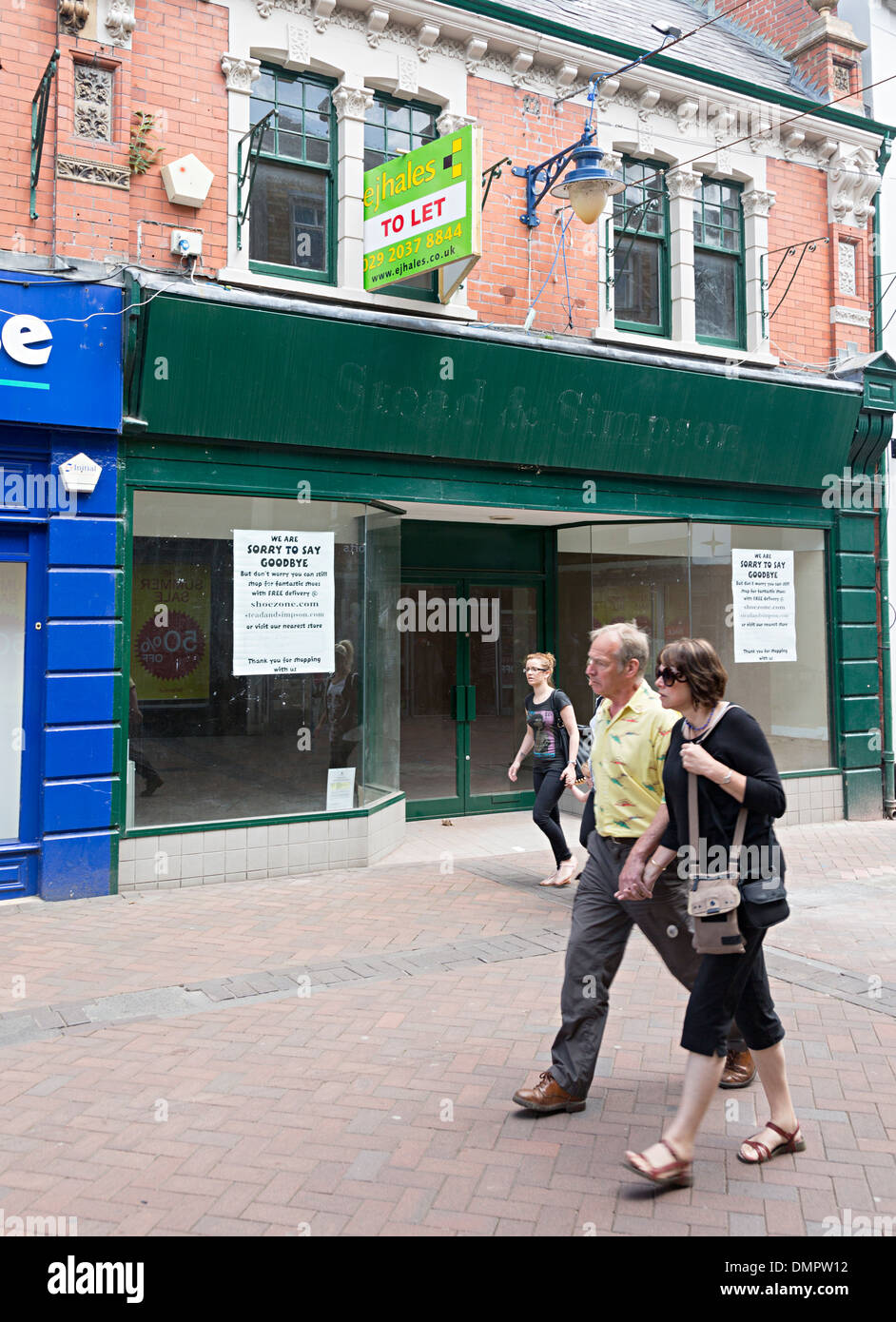 People walking past empty closed shoe shop with to let sign