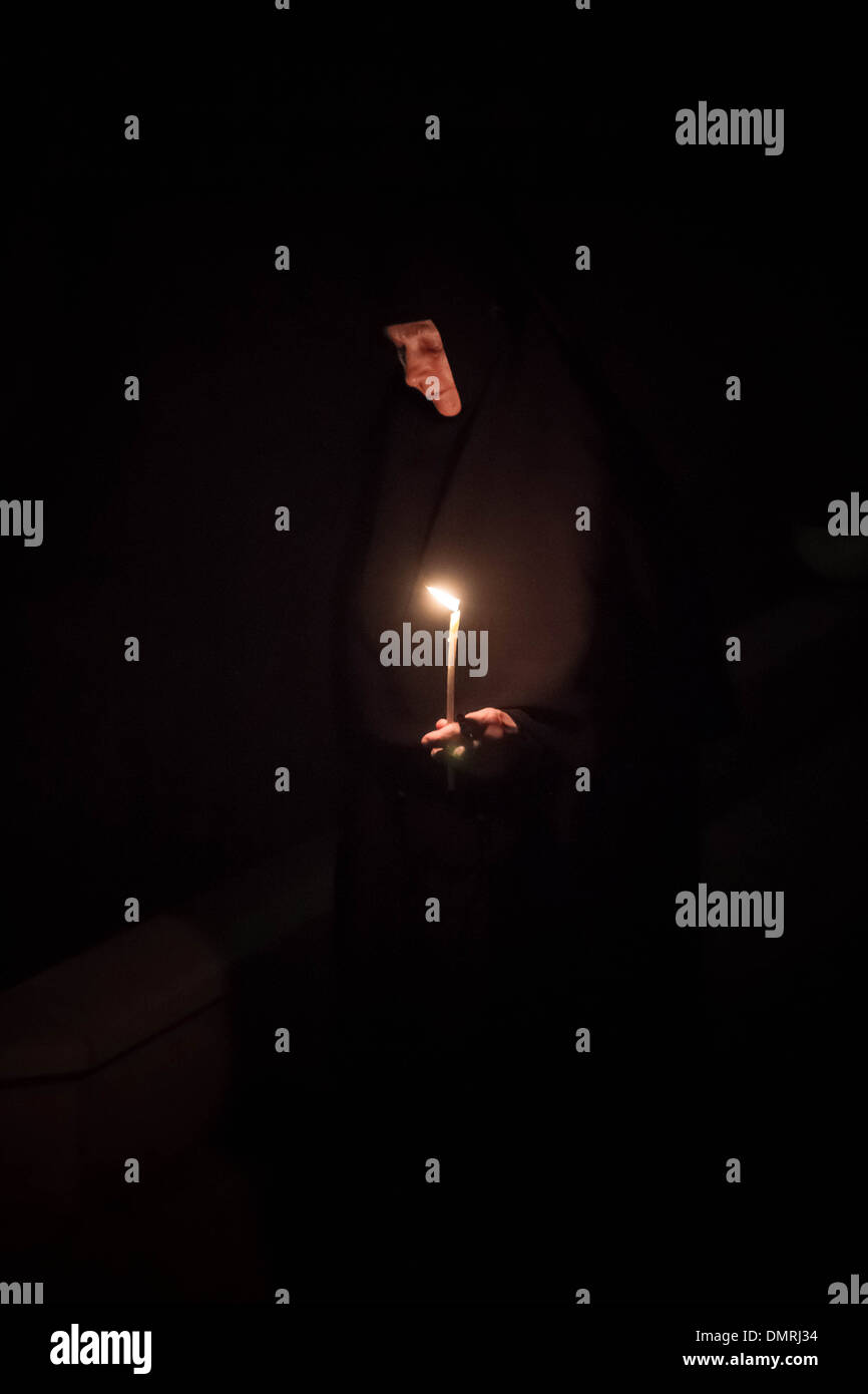 Orthodox nun with prayer candle attending a night liturgy at Gornensky