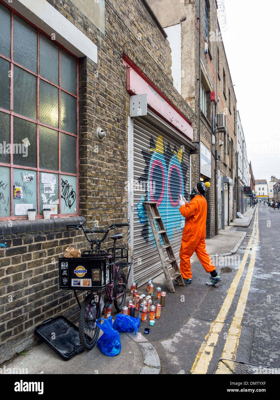 Street artist, Ronzo, at work. Artist uses spray paints to paint giant