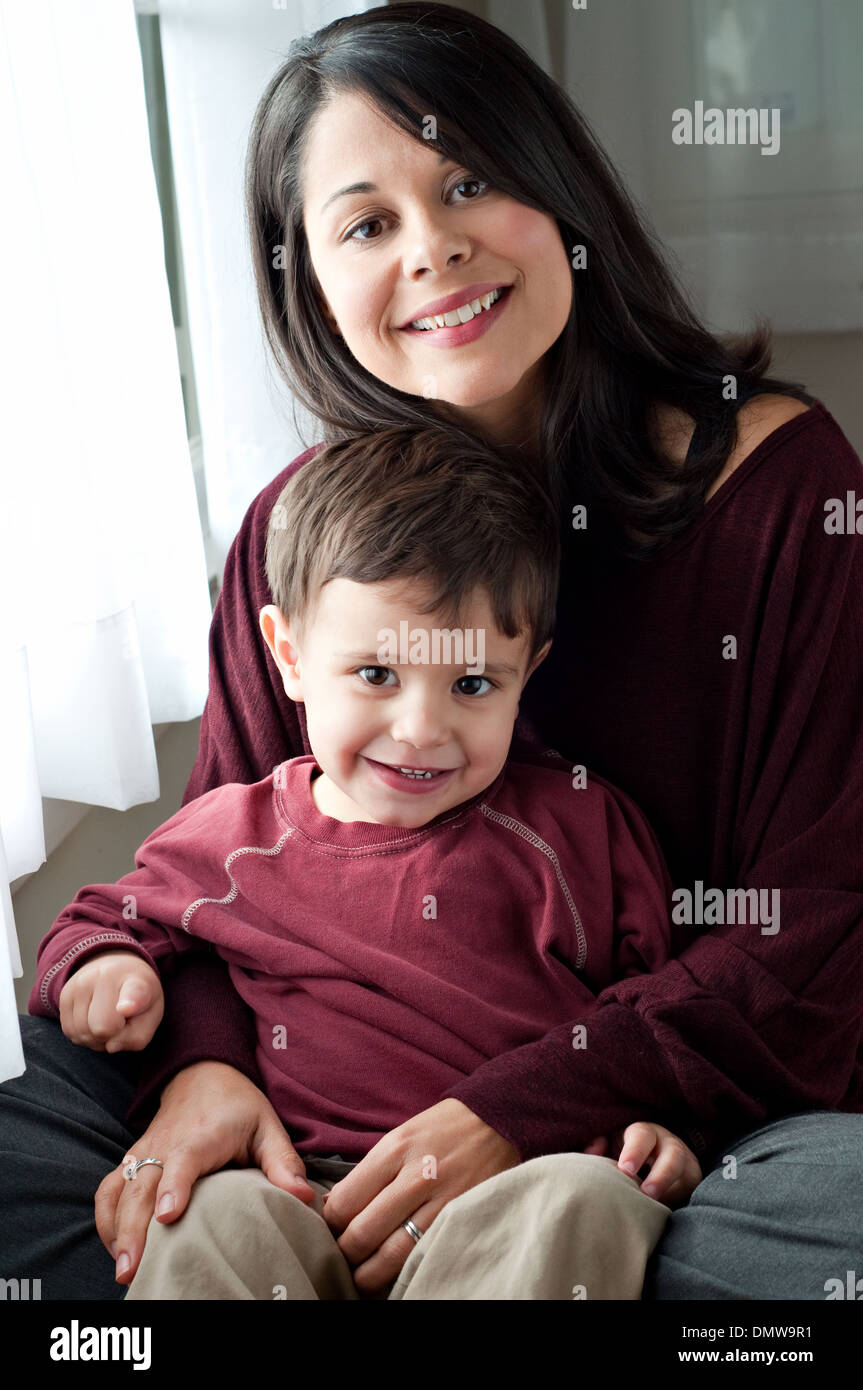 A beautiful Hispanic woman holds her playful son, smiling, pointing finger. A multiracial mother and son family portrait. Stock Photo