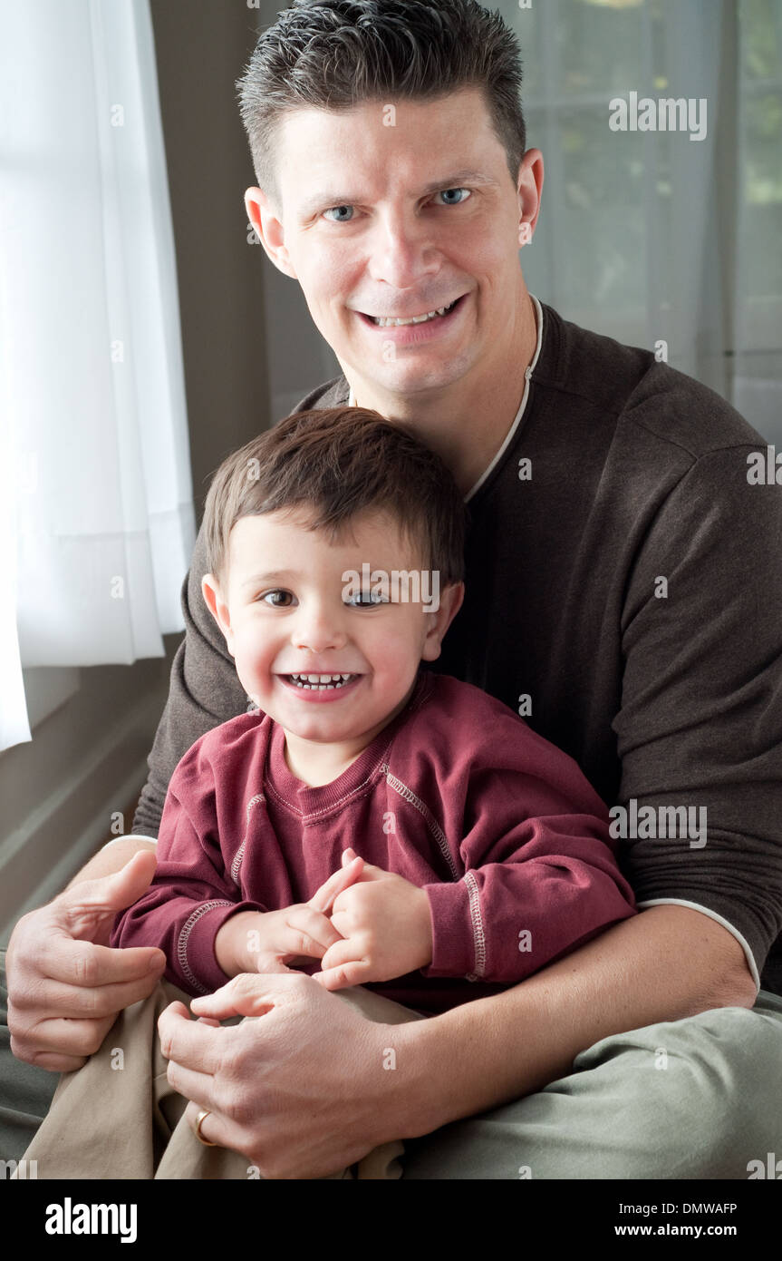 A father hugging his son, sitting and smiling, a family portrait. Stock Photo