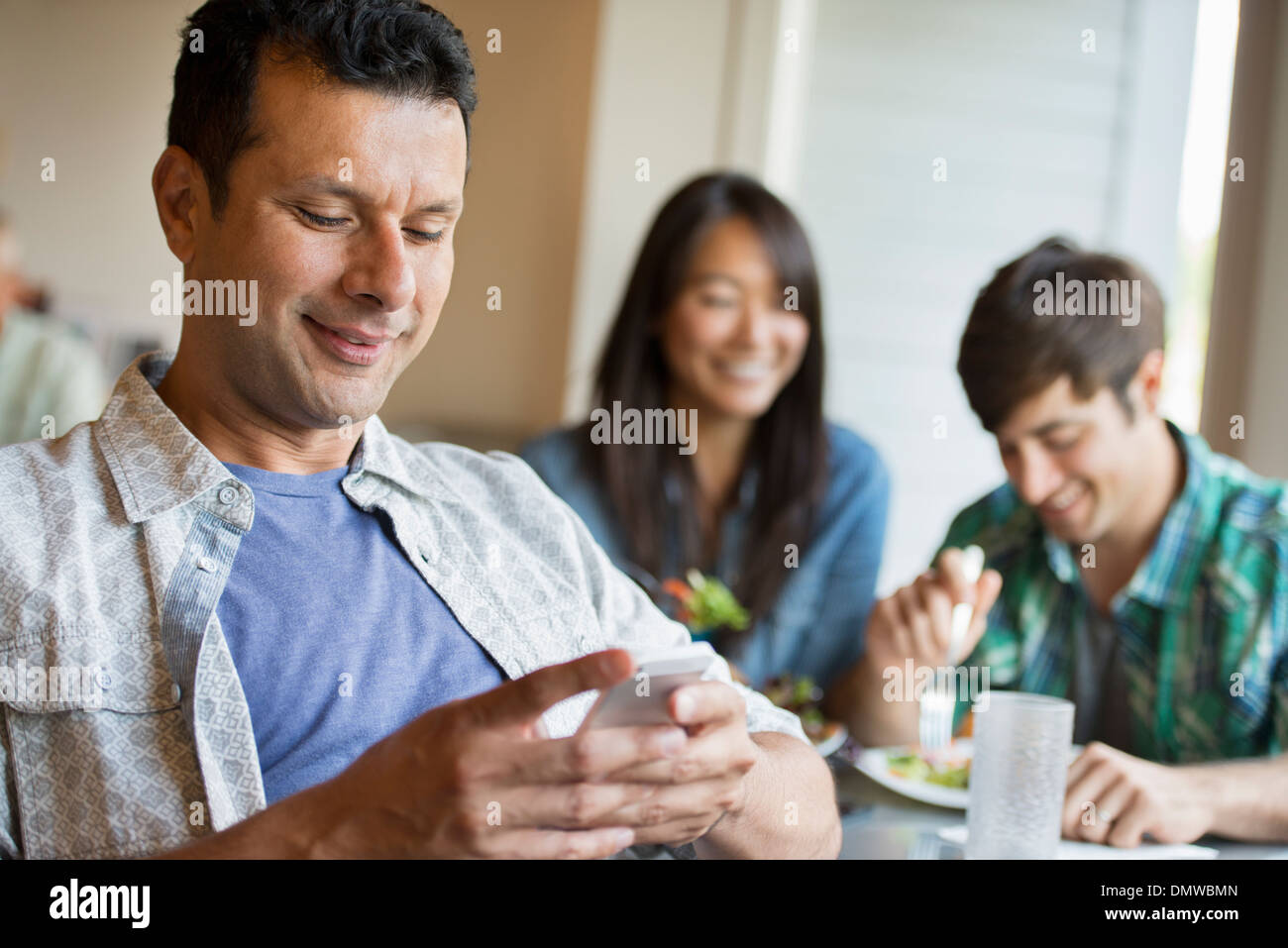Three people seated at a cafe table. Stock Photo