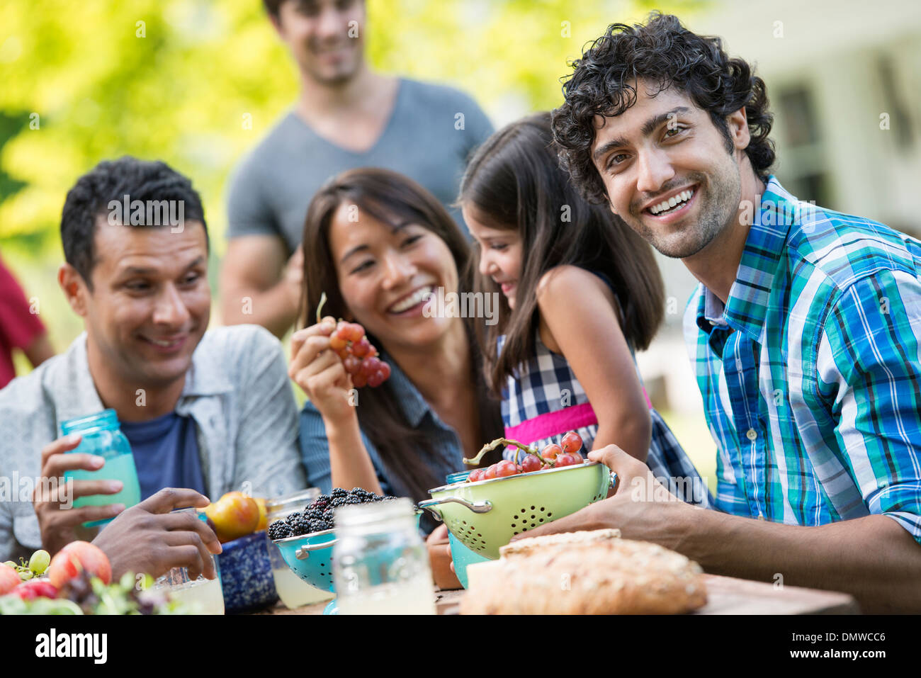 Adults and children around a table in a garden. Stock Photo