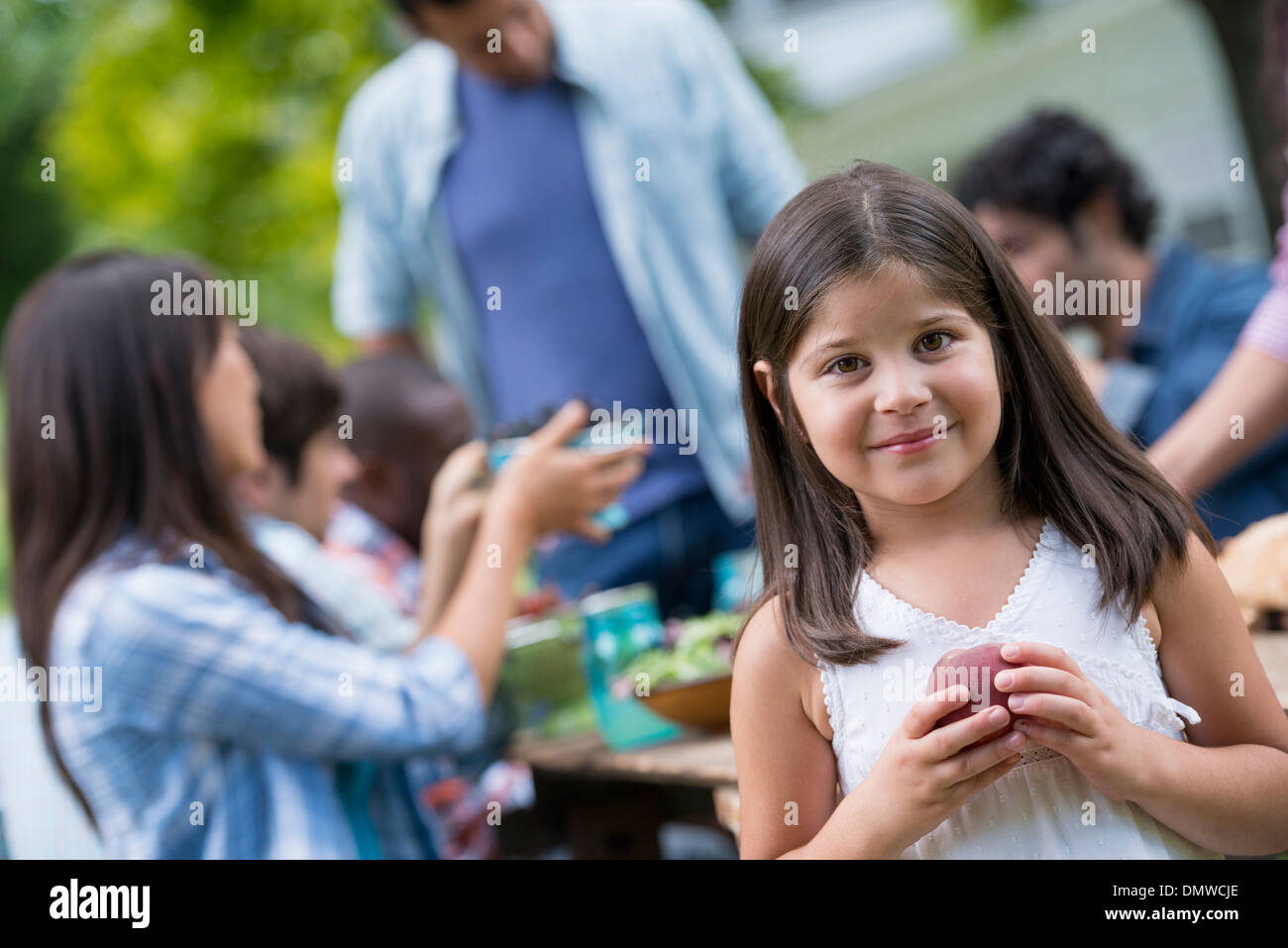 A summer party outdoors. Adults and children around a table. Stock Photo