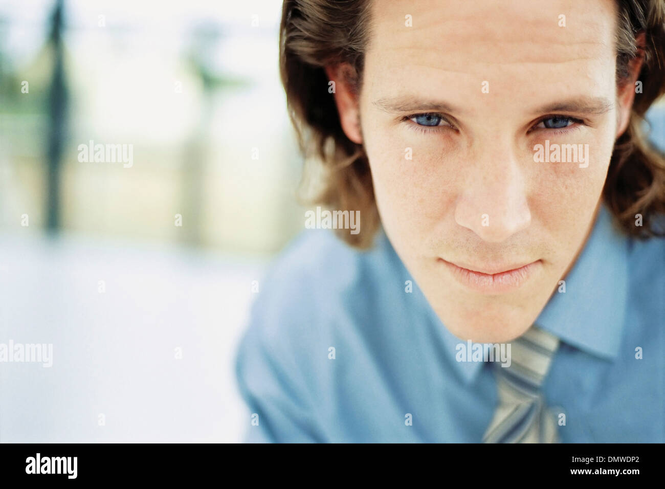 A young man with curly brown hair wearing a blue shirt and tie Stock ...