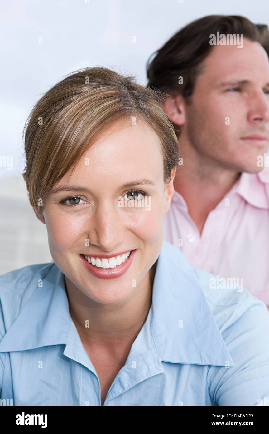 A young couple a woman in  foreground smiling and a man looking into  distance. Stock Photo