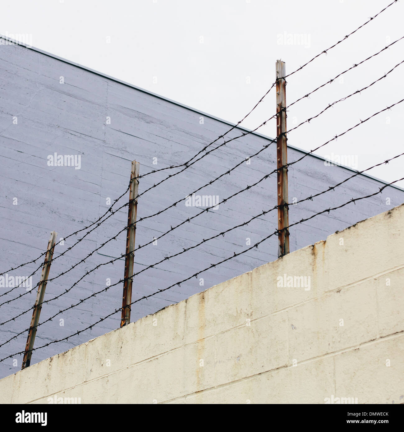 Barbed wire fence at  top of a wall in a city. Stock Photo