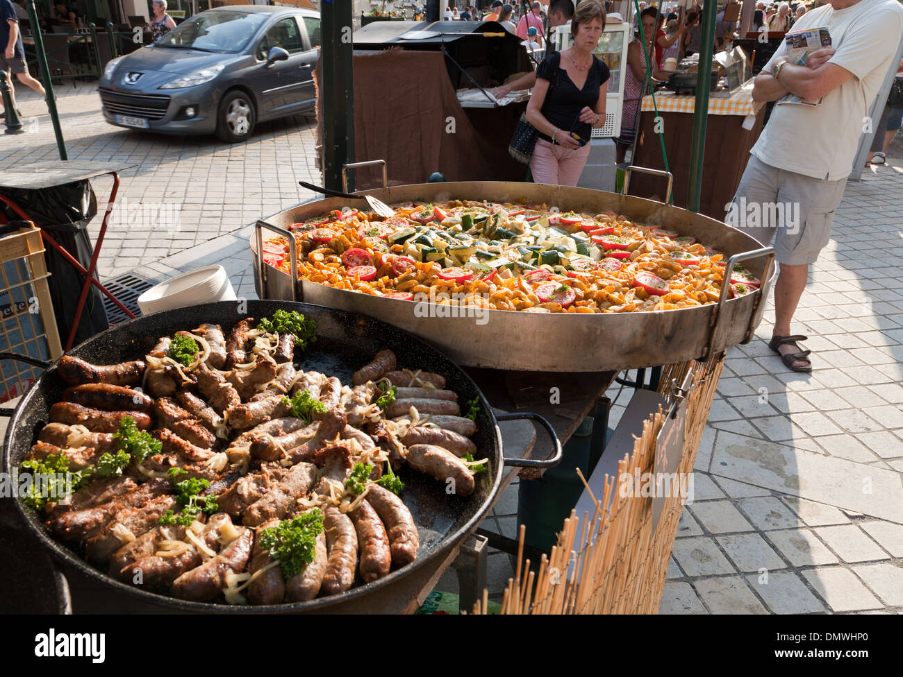 Amboise summer evening market, two large pans of food cooking, sausages ...