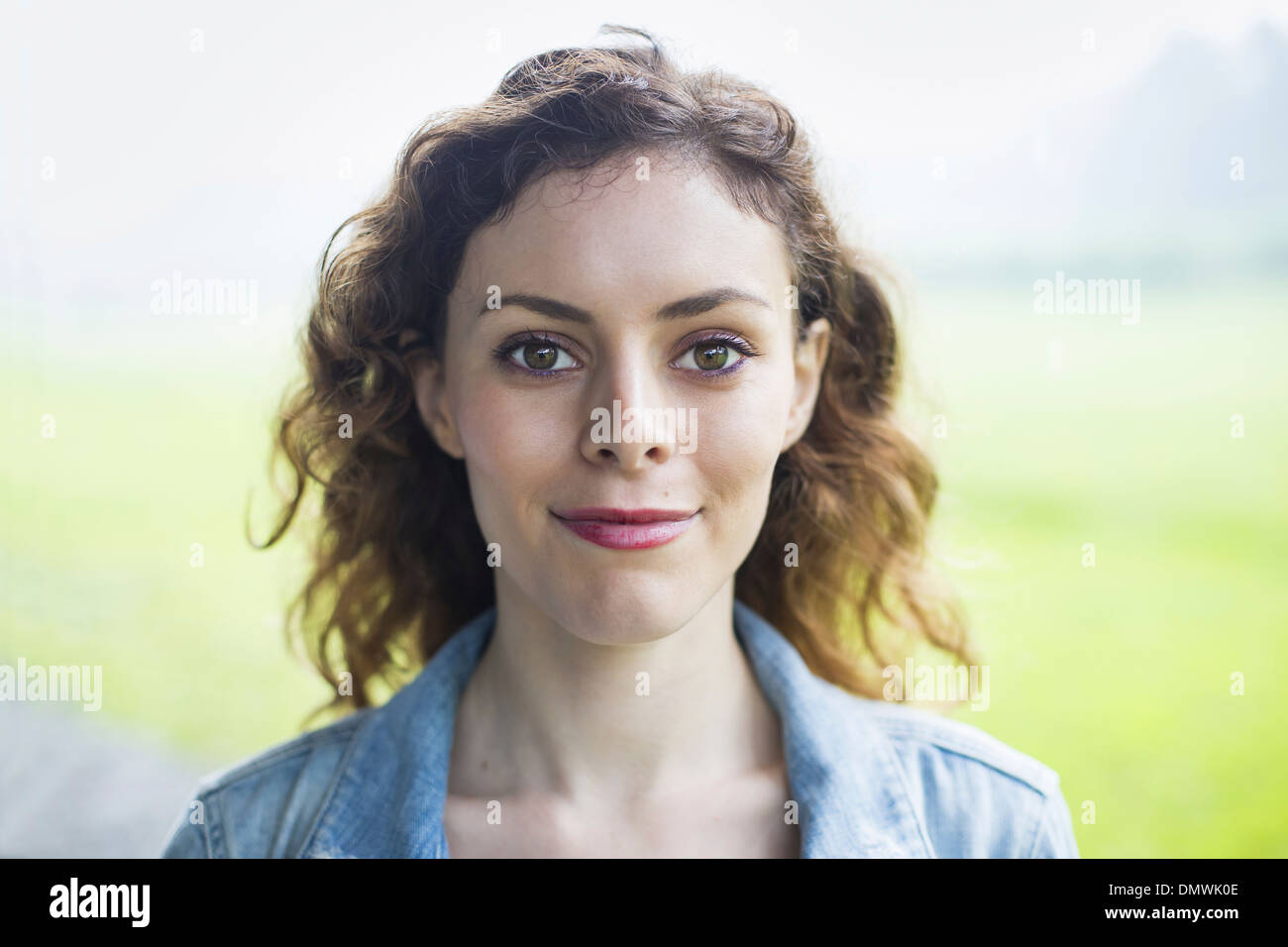 A young woman in a rural landscape with windblown curly hair smiling. Stock Photo