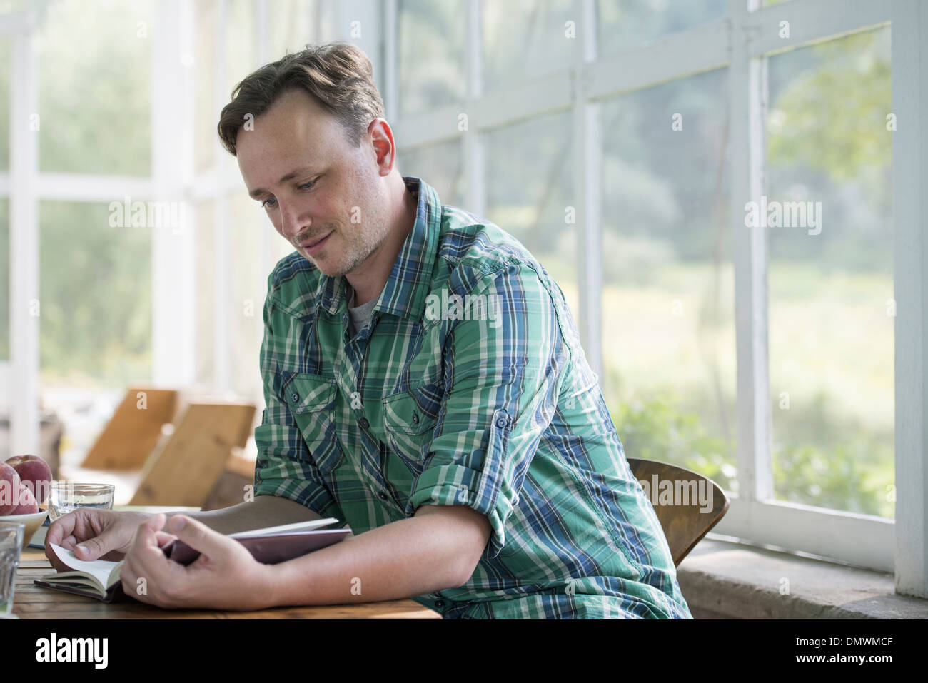 A man sitting at a table reading a book. Stock Photo