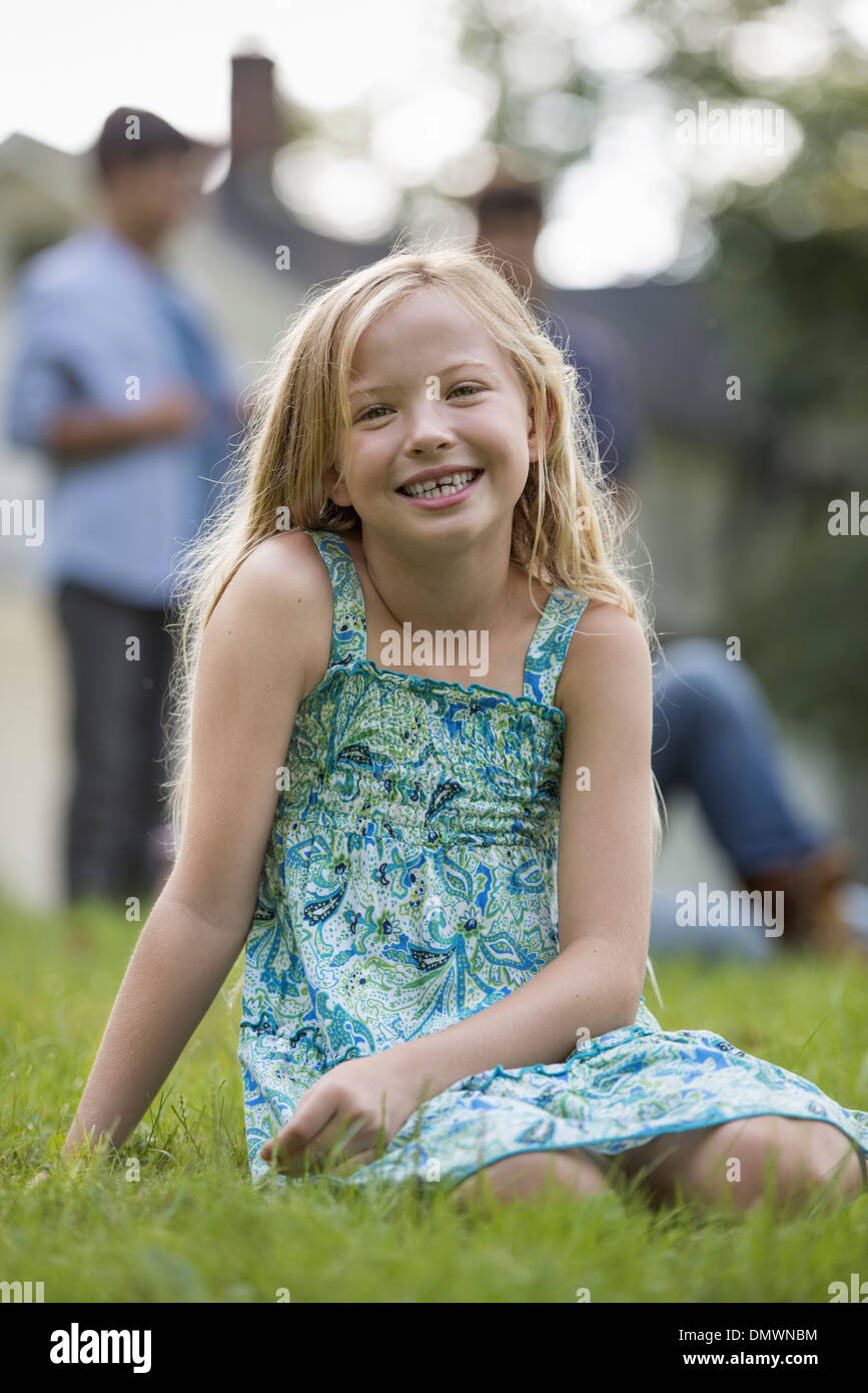 A child sitting on  grass at a summer party. Stock Photo
