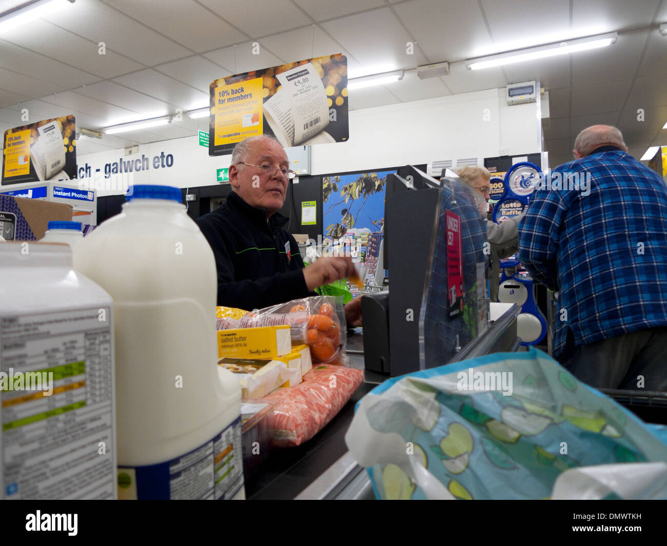 An elderly senior male man worker working at the checkout counter in the Co-Operative (Co Op) supermarket in Britain UK   KATHY DEWITT Stock Photo