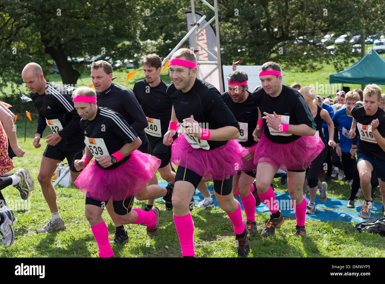 Male competitors dressed in pink skirts wearing head bands at the  starting line of an endurance race in  Derbyshire UK Stock Photo