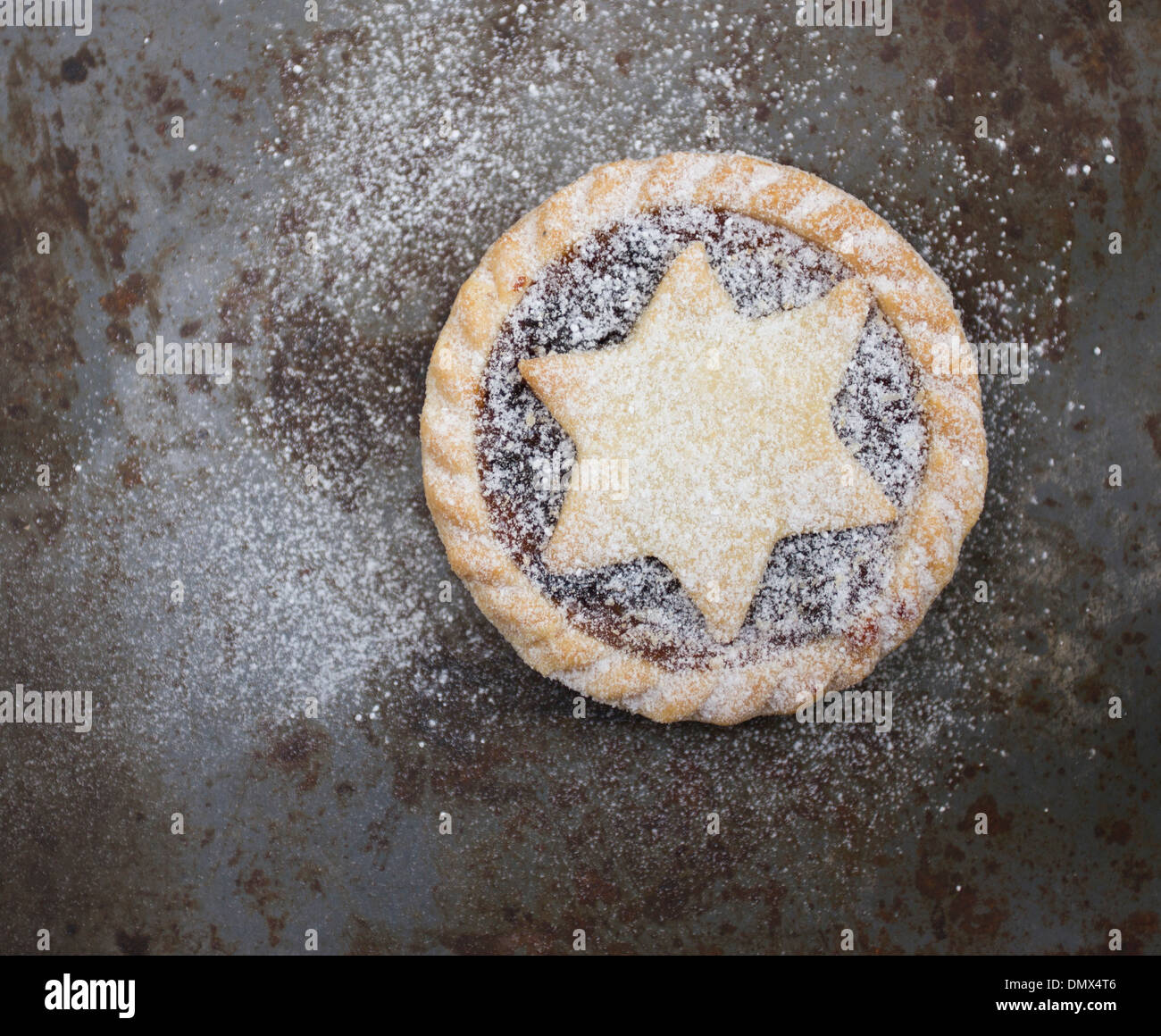 Single home made icing sugar dusted mince pie on grey rustic metal surface Stock Photo