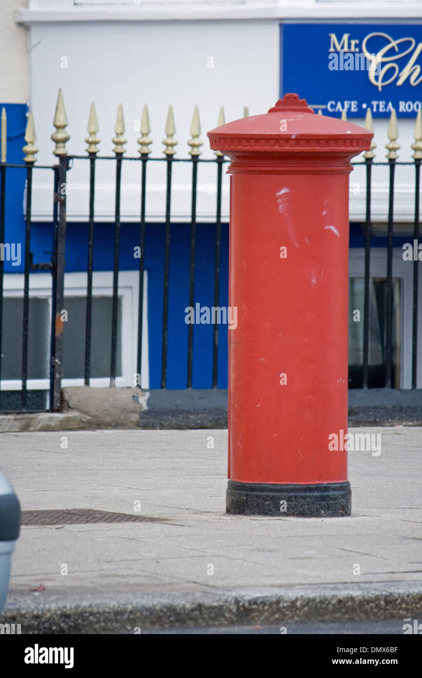 post box in front of spiked railings in front of a blue and white