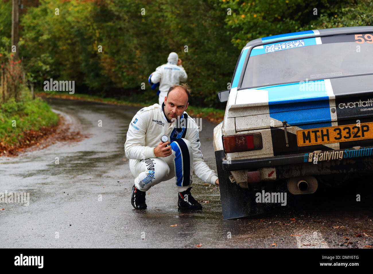 Male pilot checking tire air pressure during a rally race car. Condroz rally race in Belgium, 2013 Stock Photo