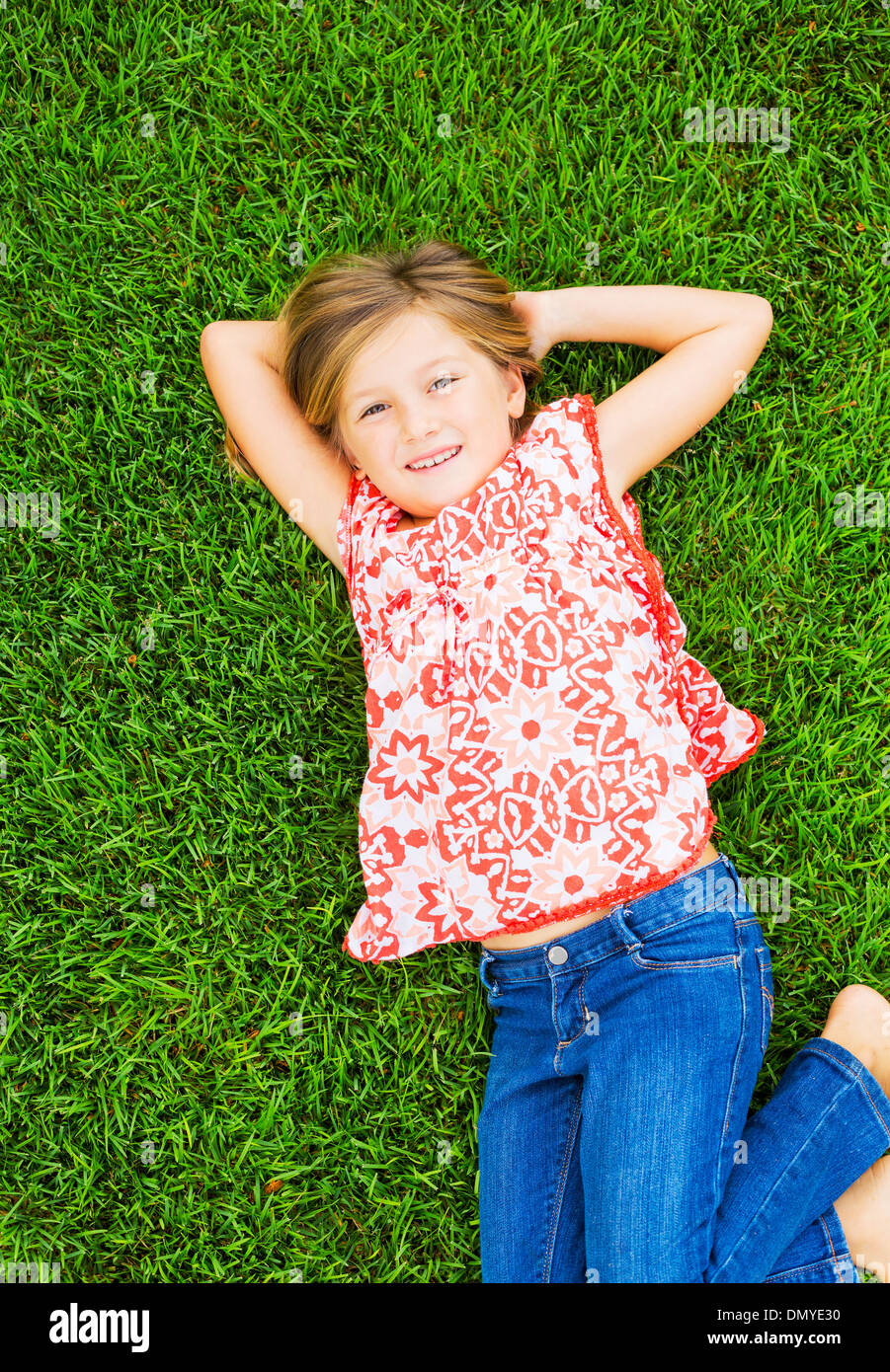 Cute smiling little girl relaxing on green grass Stock Photo - Alamy