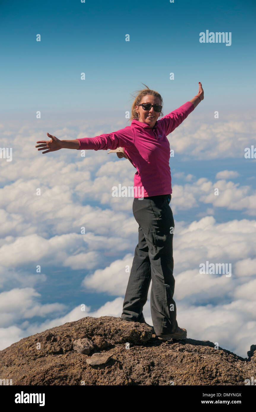 A happy trekker above the clouds on the route to the summit of Kilimanjaro Stock Photo