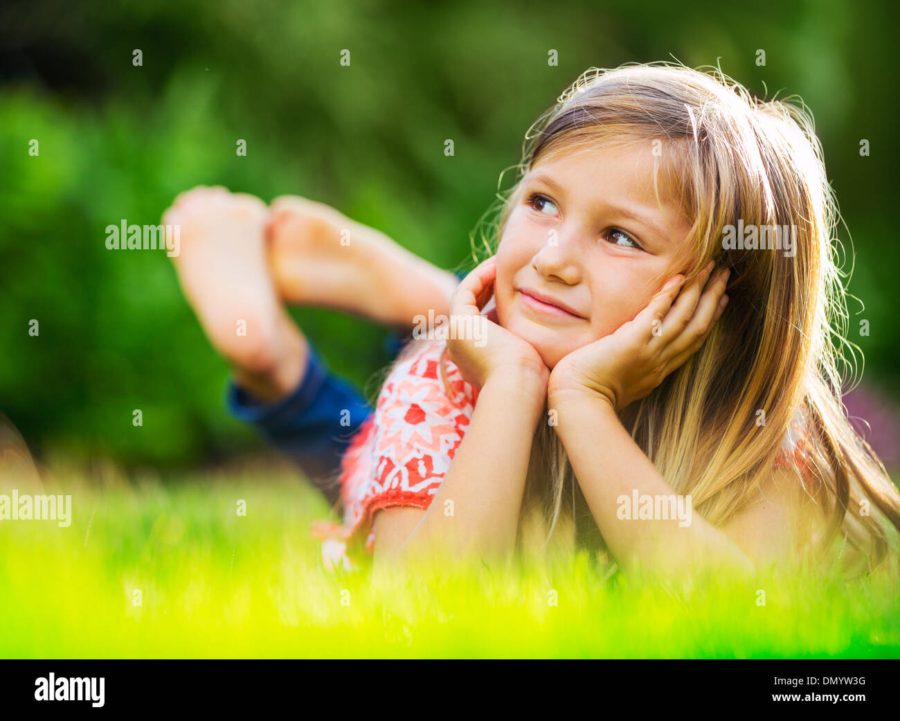 Portrait of a smiling little girl lying on green grass Stock Photo - Alamy