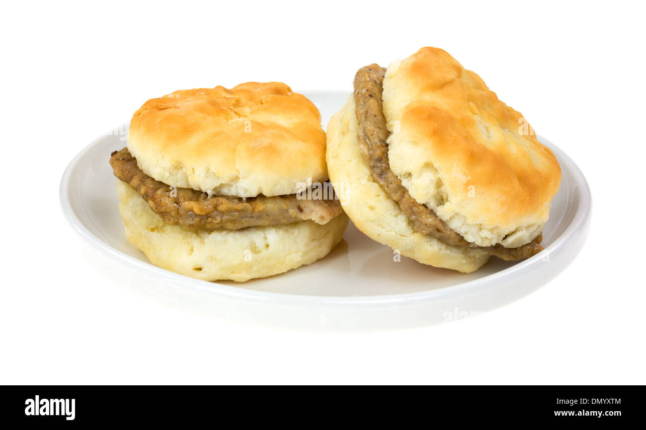 Two very small buttermilk biscuits with sausage patties on a dish. Stock Photo