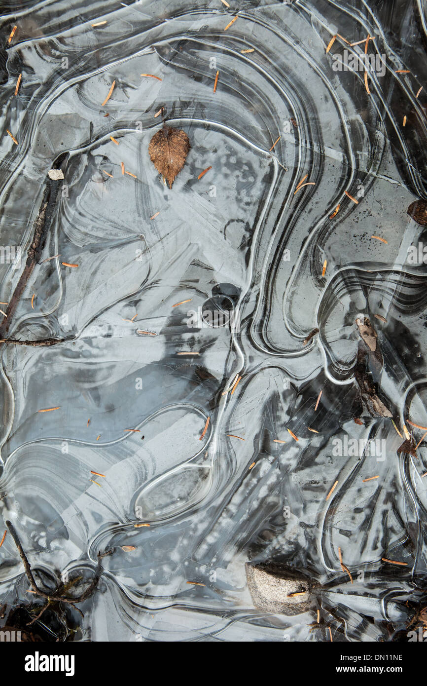 Curving frozen ice patterns on the edge of a creek in early winter. Stock Photo