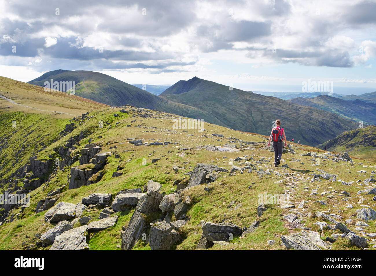 A hiker walking off Great Carrs towards the Old Man of Coniston and Dow Crag in the Lake District. Stock Photo