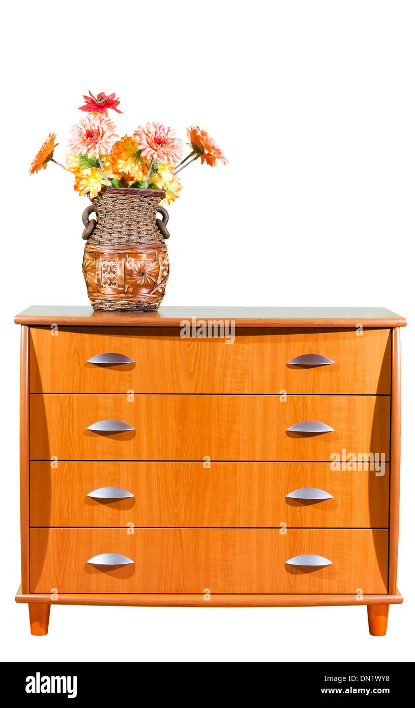 Artificial flowers in a big vase on top of a closet with four drawers. Stock Photo