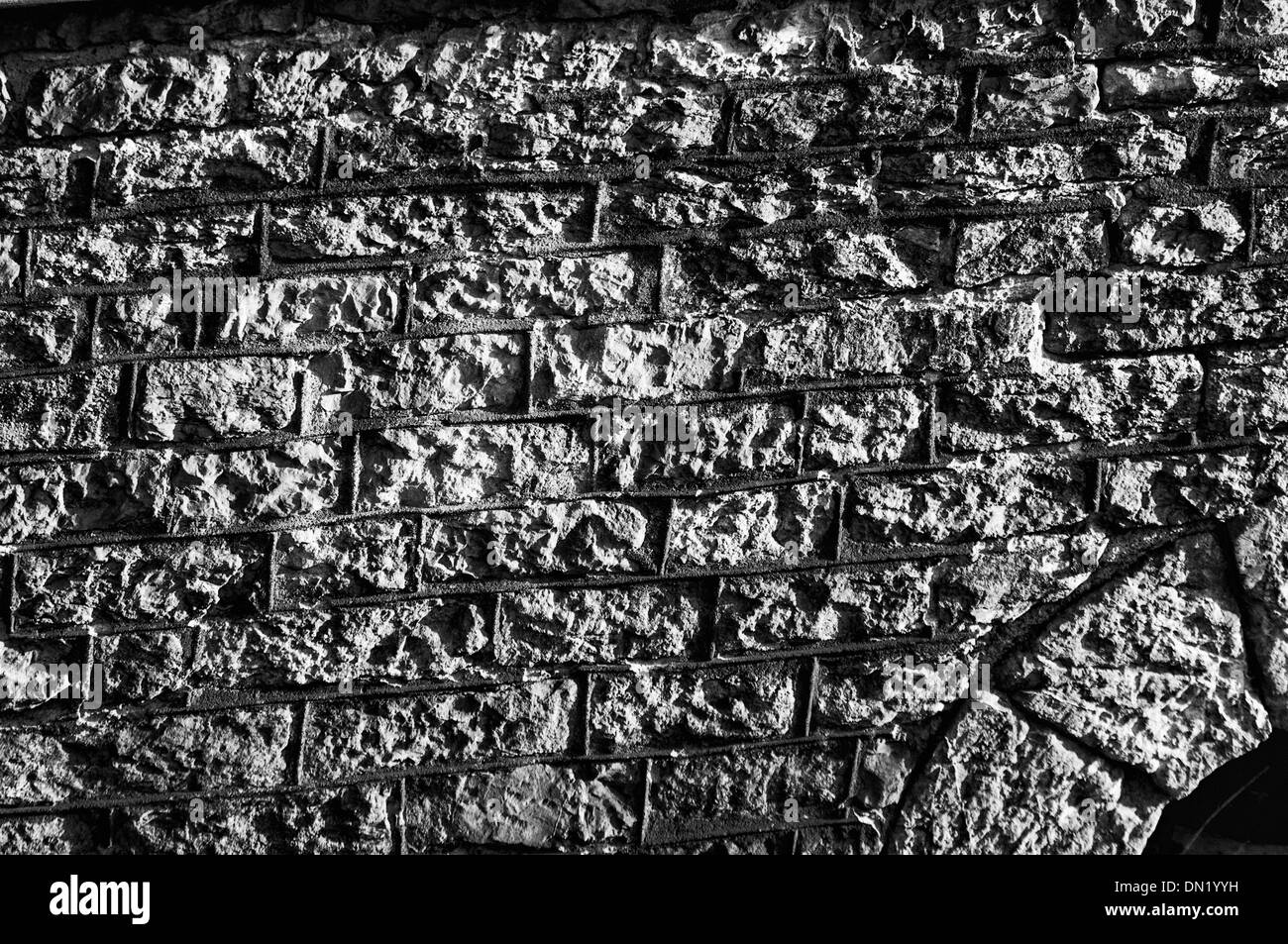 Black & White photo showing the texture of a heavily worn sandstone block wall Stock Photo