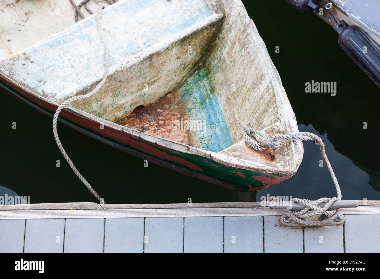 Closeup of the bow of an old boat tied with rope to a cleat on a