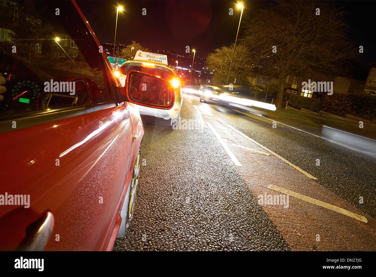 Learner driver on a busy road at night. Stock Photo