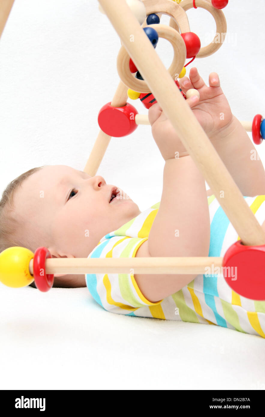 Beautiful baby on back playing with toys Stock Photo