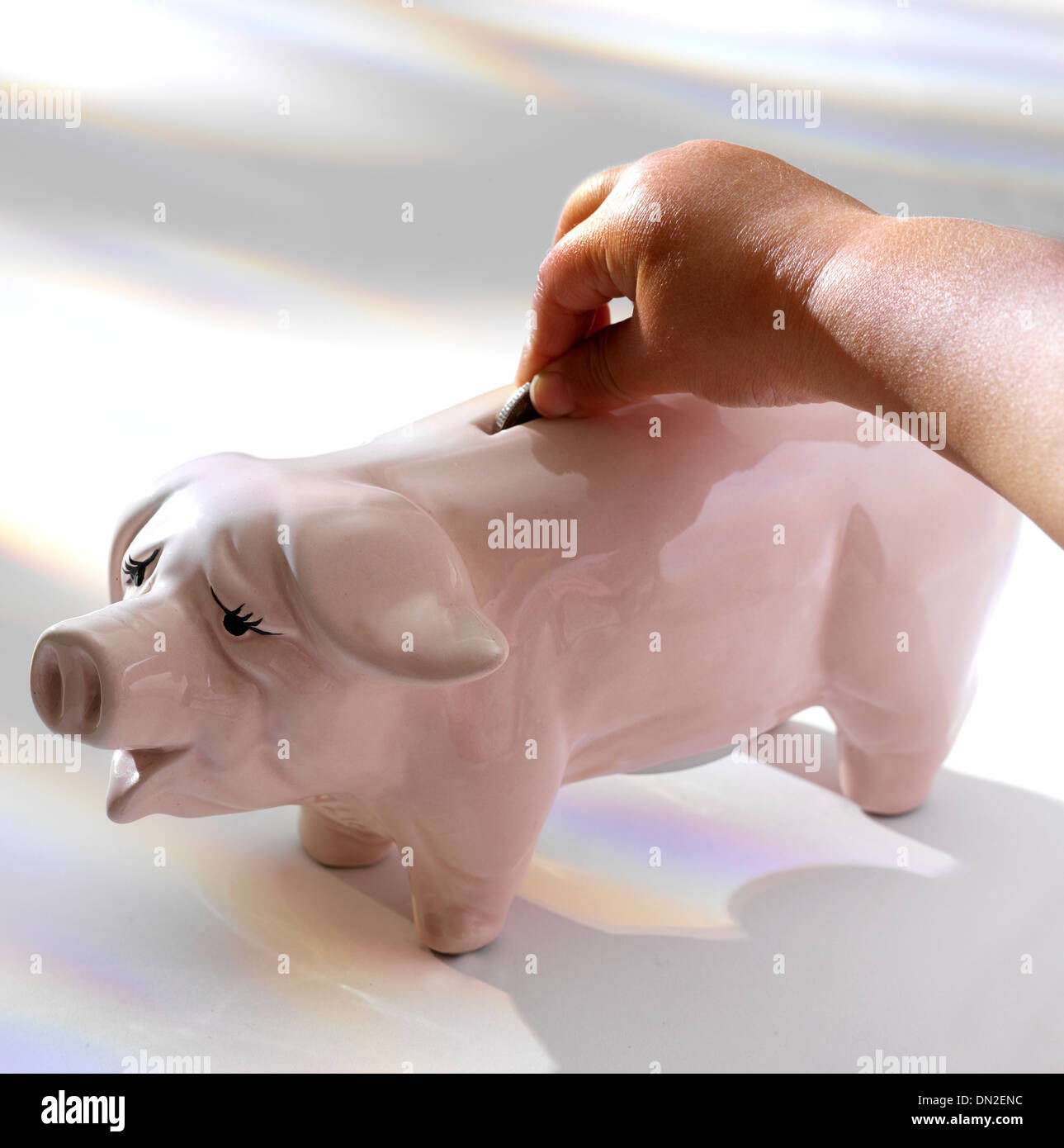 Child putting a coin in a piggy bank Stock Photo