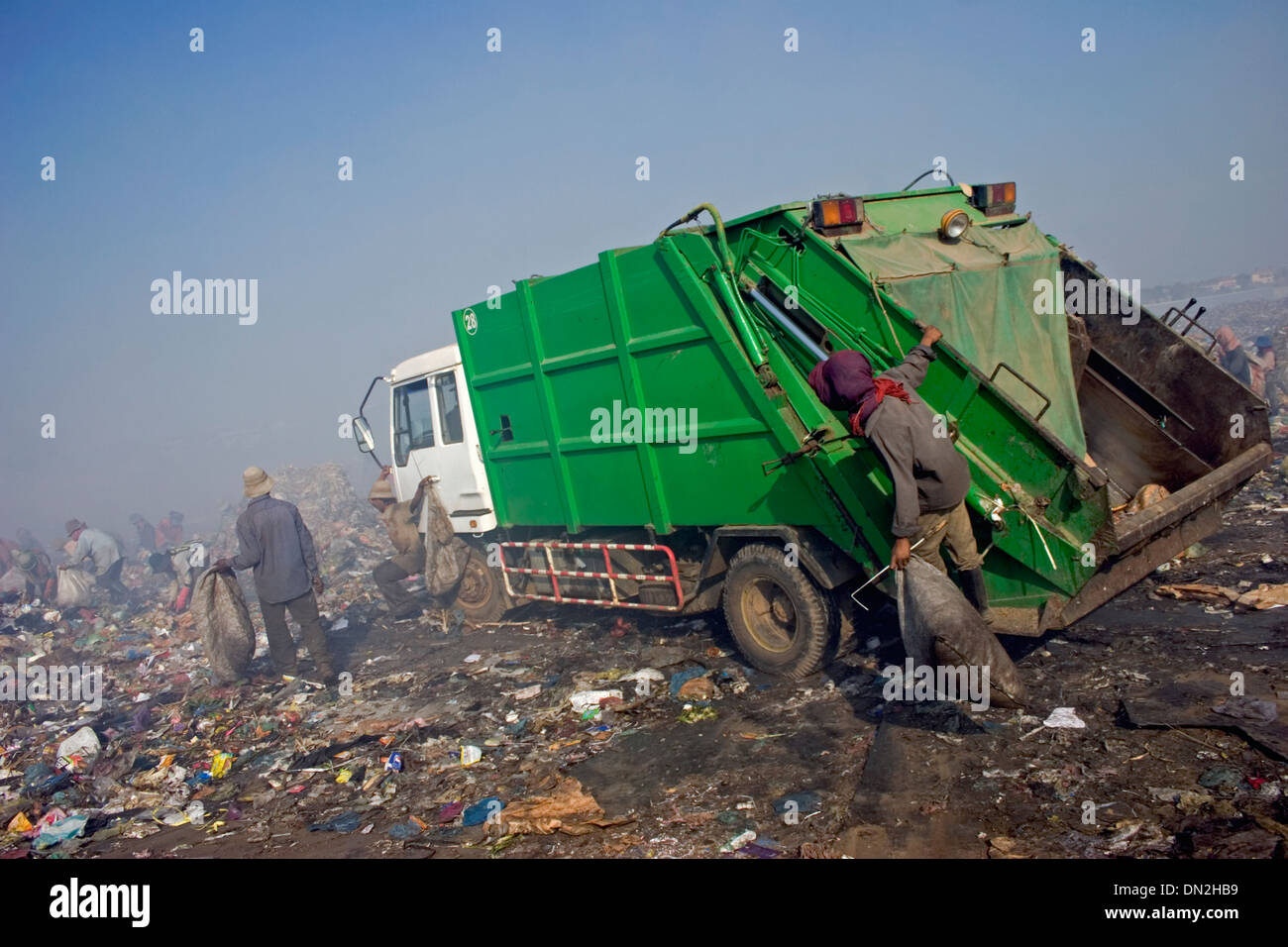 A young man is hanging on to a garbage truck at the Stung Meanchey Landfill in Phnom Penh