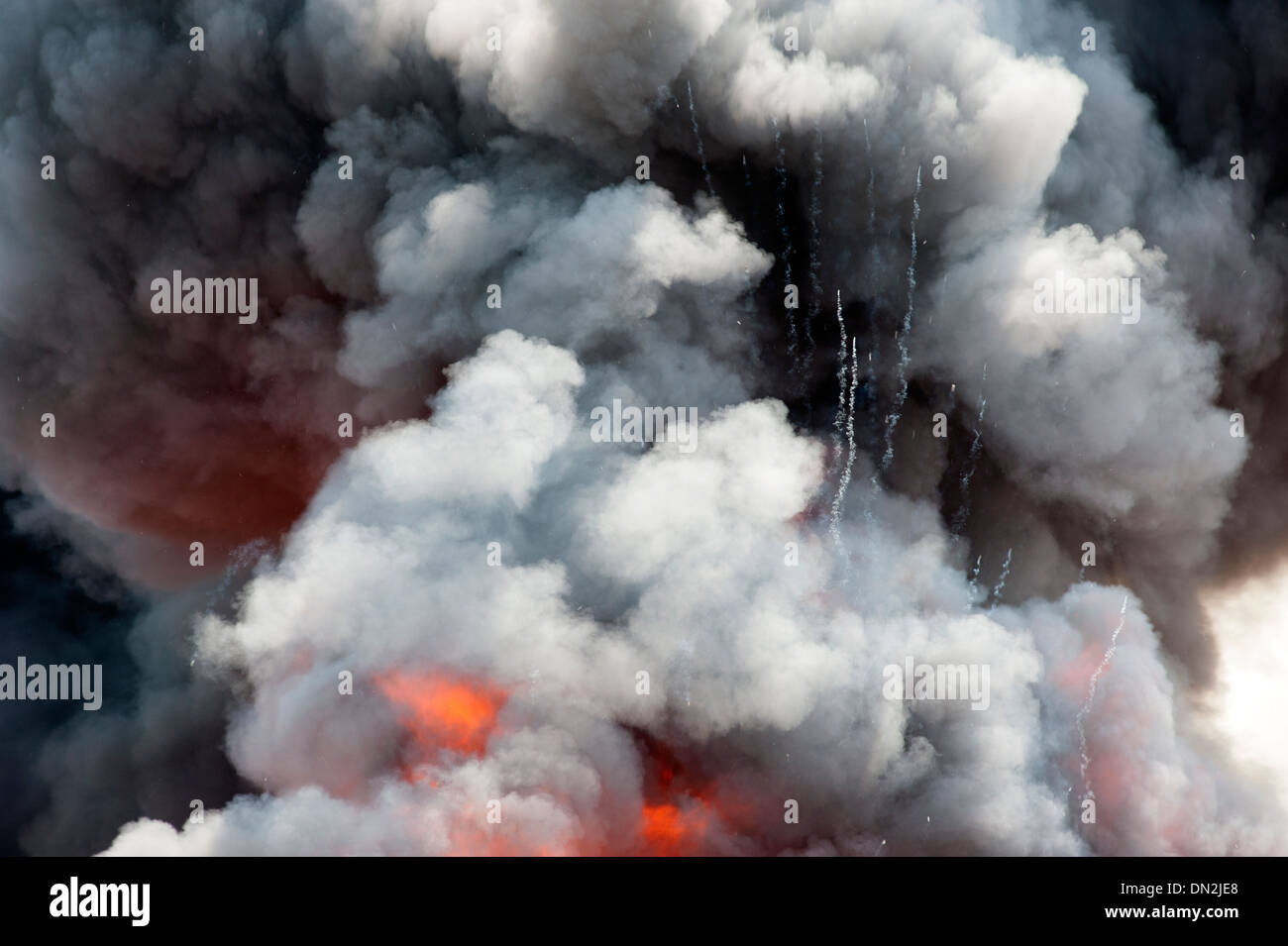Aerosol cannisters exploding in large fire smoke Stock Photo