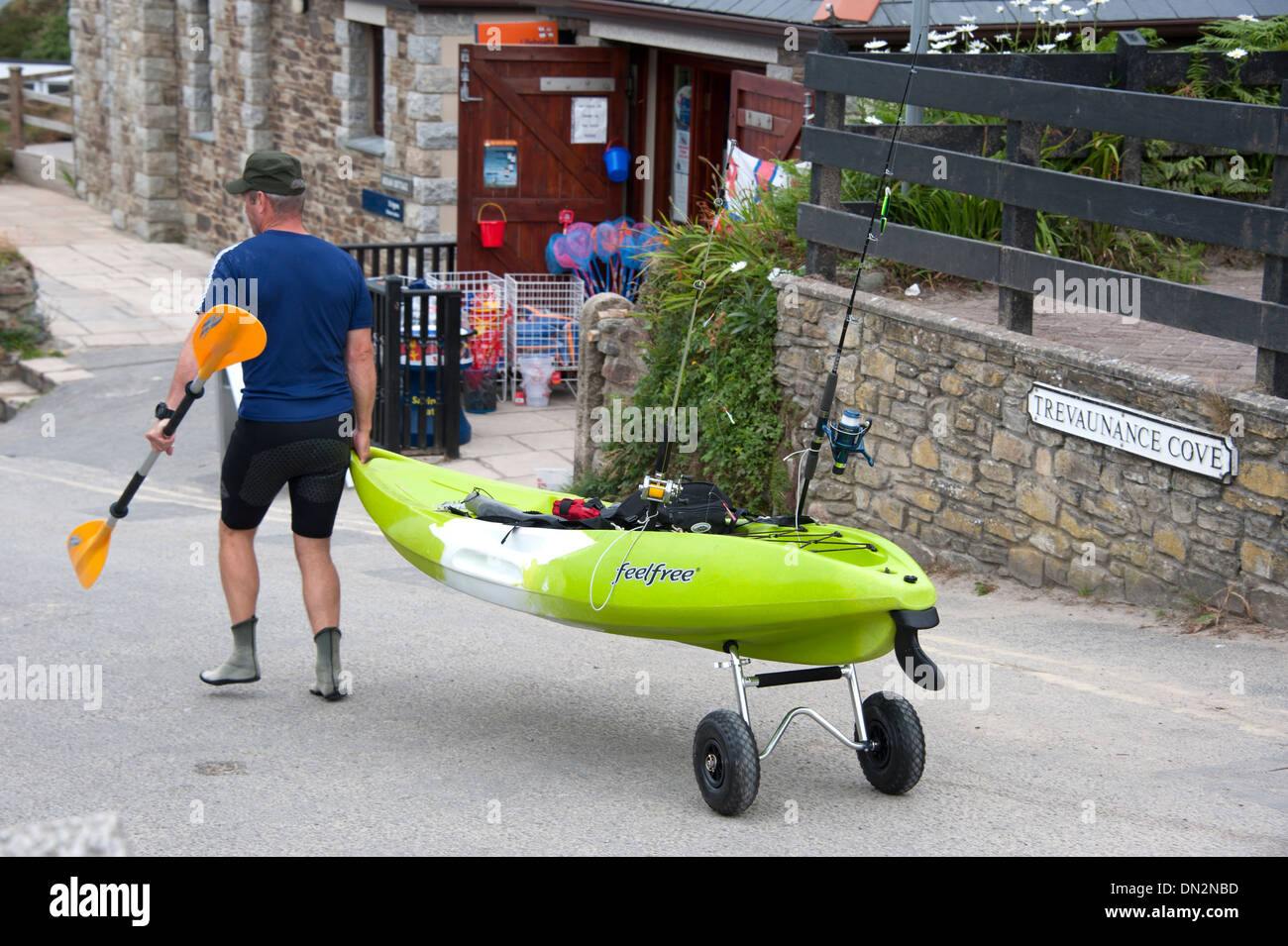 Man wheeling Kayak Fishing Trevaunance Cove Cornwall Stock Photo
