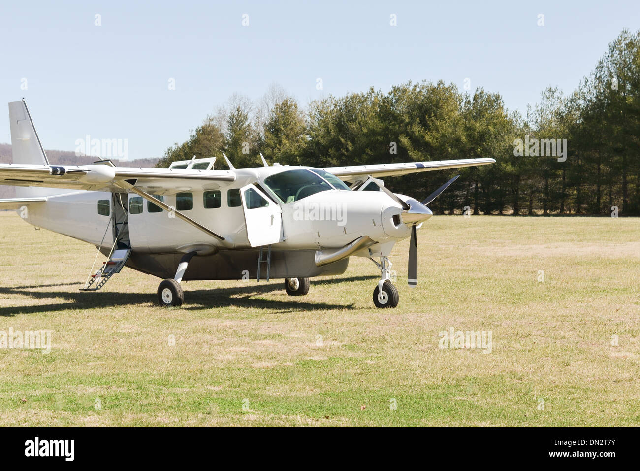 A Cessna Caravan private aircraft is ready for boarding on a grass