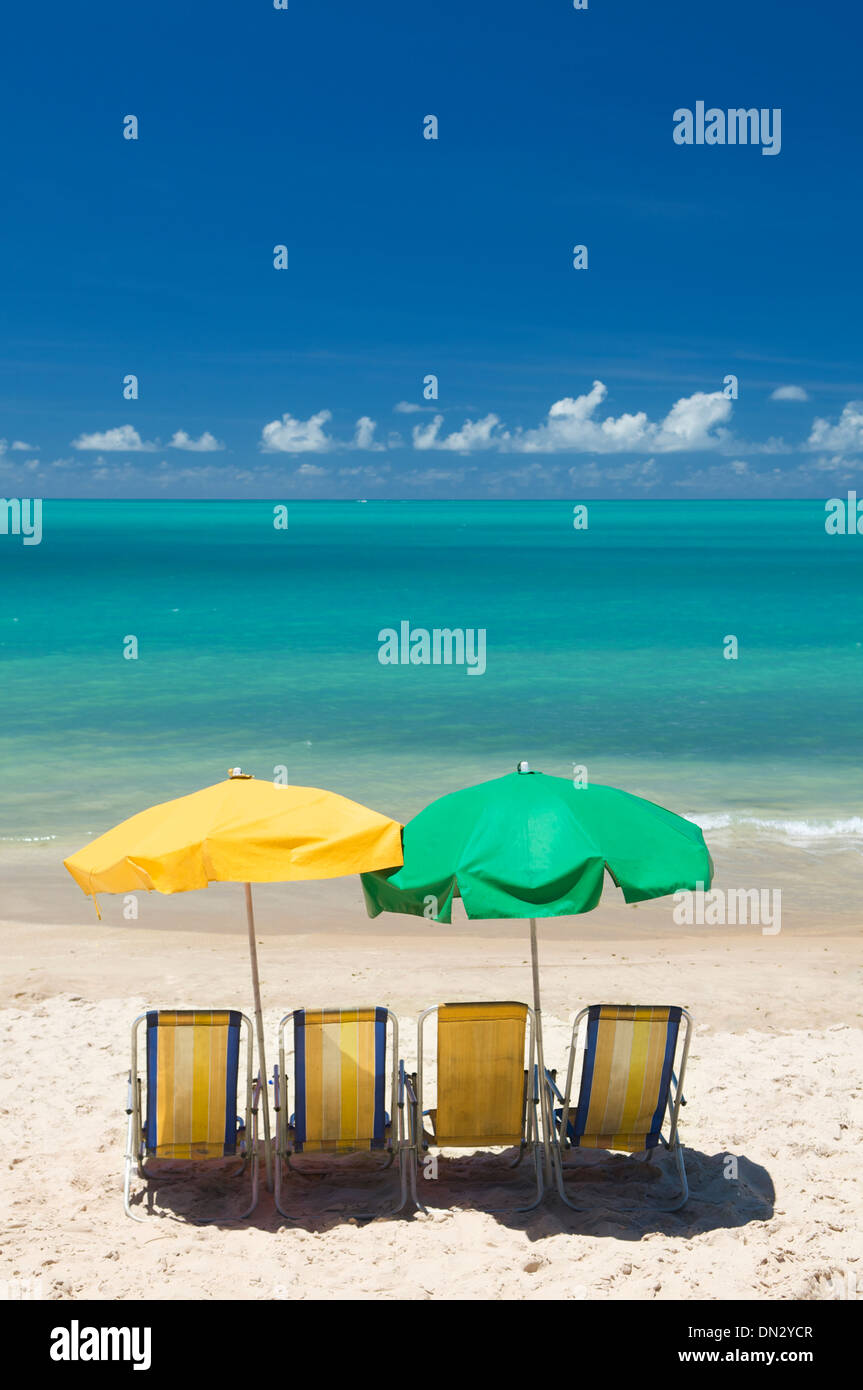 Tropical beach scene with four beach chairs and two umbrellas in Nordeste Brazil Stock Photo