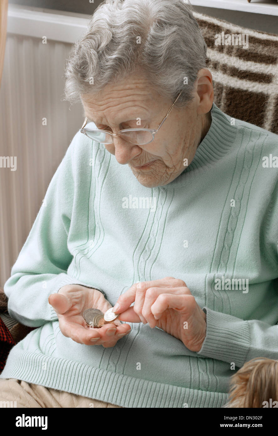 Elderly woman holding a mixture of coins (going through money in the age of austerity) Stock Photo