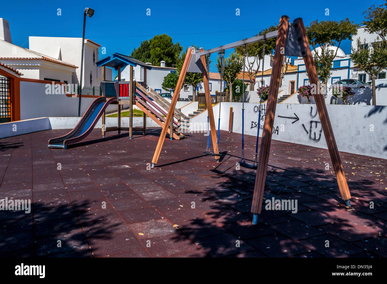 an empty children's playground with slides and swings with graffito on the wall, Stock Photo