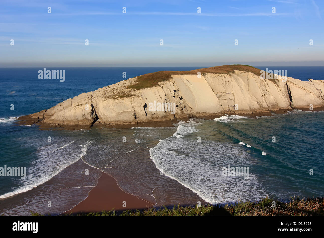island connected by a sand spit to the coast, with waves on two sides