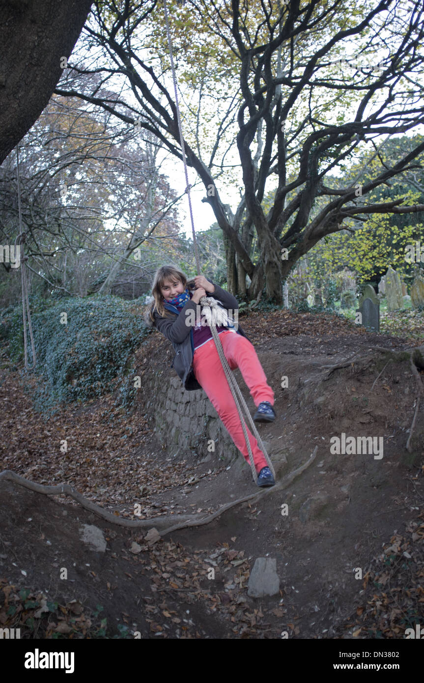 An 11 year old girl swings on a rope Stock Photo