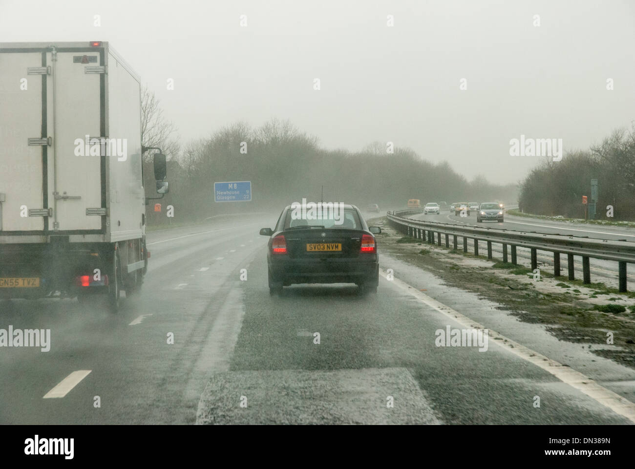 Vehicles drive along motorway in wet winter conditions in United Kingdom Stock Photo