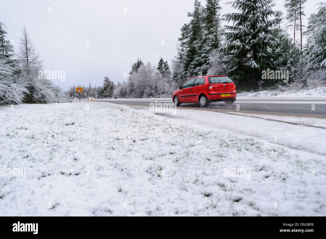 Car drives along snow covered trunk road in daylight in winter conditions in UK Stock Photo