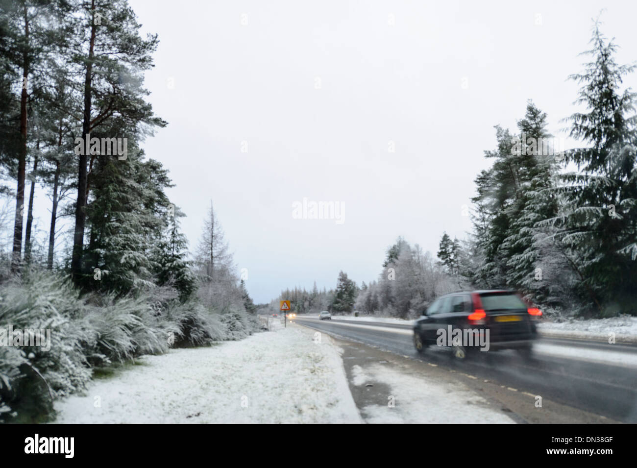 Car drives along snow covered trunk road in daylight in winter conditions in UK Stock Photo