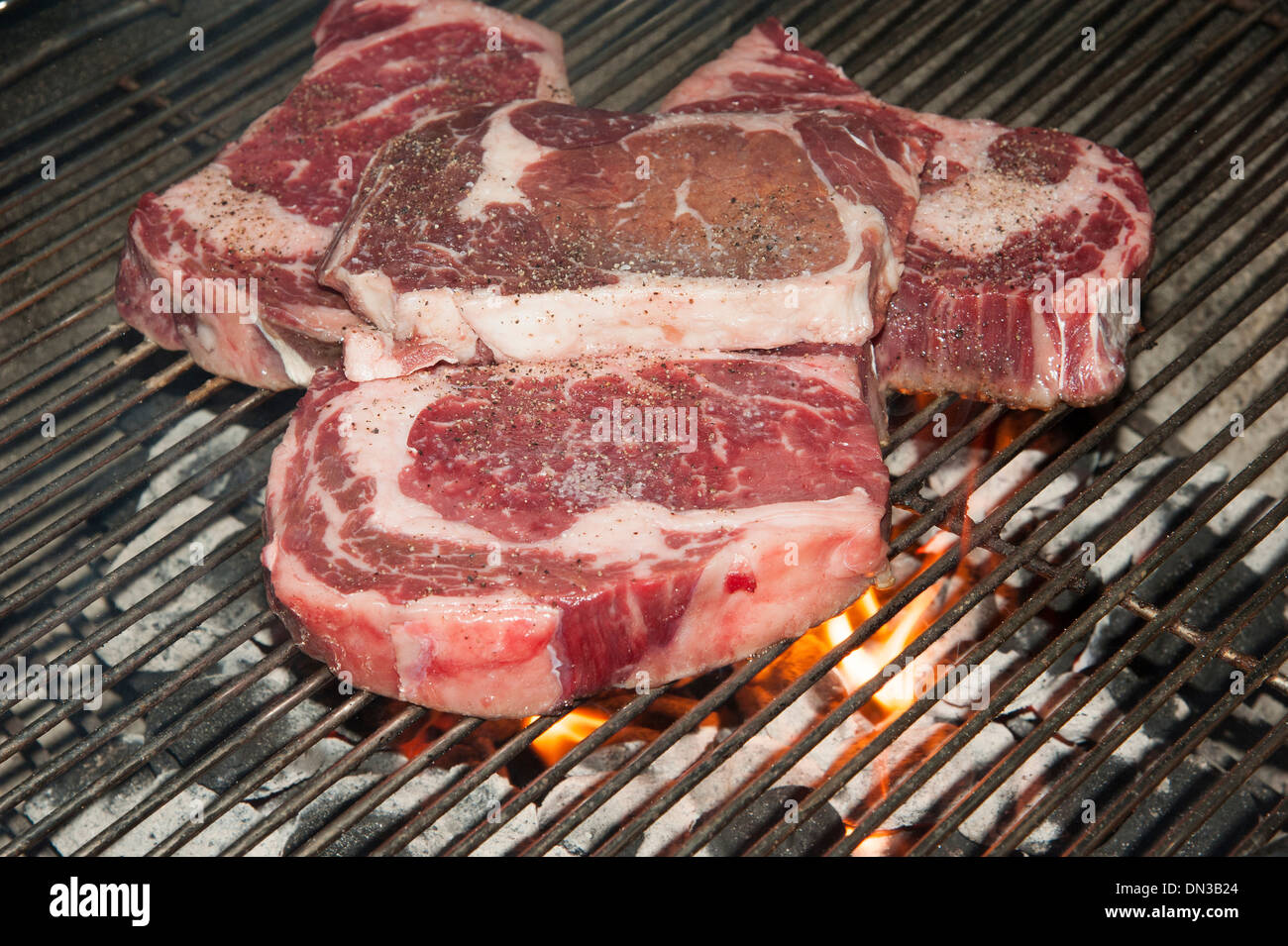 American Ribeye steaks cooking over coals on a barbecue Stock Photo Alamy