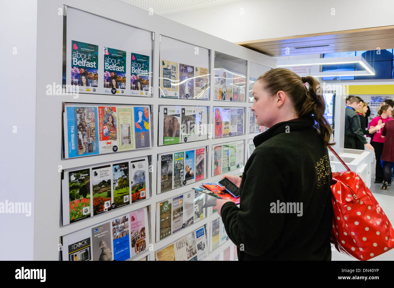 A woman browses the tourist information leaflets in Visit Belfast tourist information centre Stock Photo