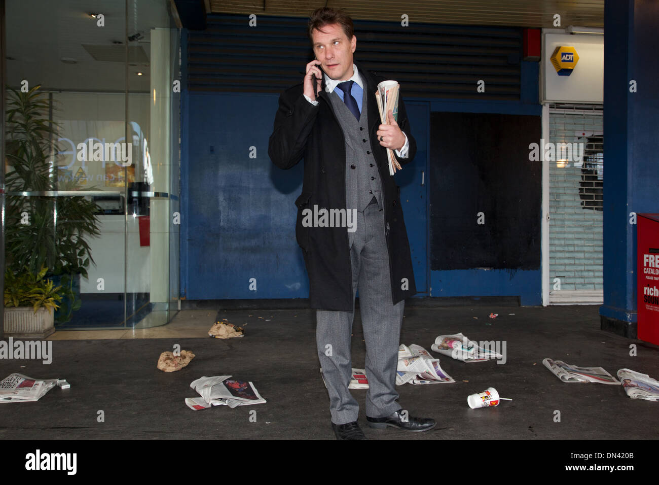A smirking City of London businessman speaking on his mobile phone surrounded by rubbish Stock Photo
