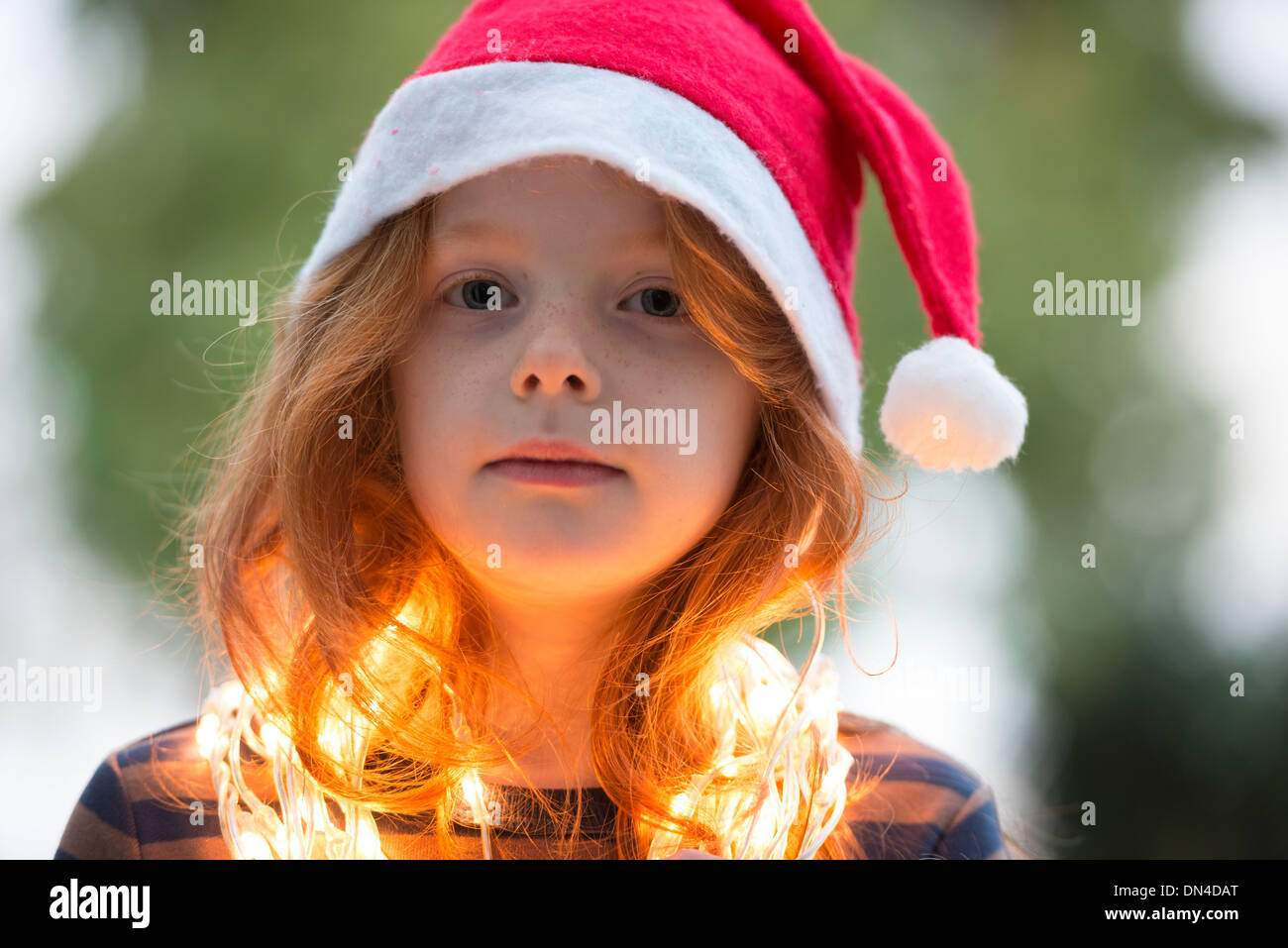 A little girl dressed in a santa hat and fairy Christmas lights Stock ...