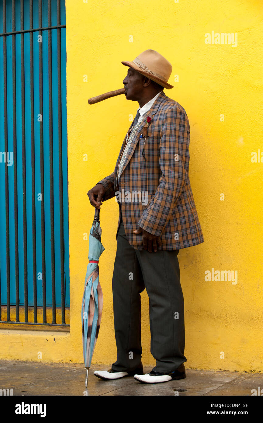 Profile man of color black smiling holds cigar in hand umbrella plaid jacket traditional dress in Havana Cuba street tourism Stock Photo