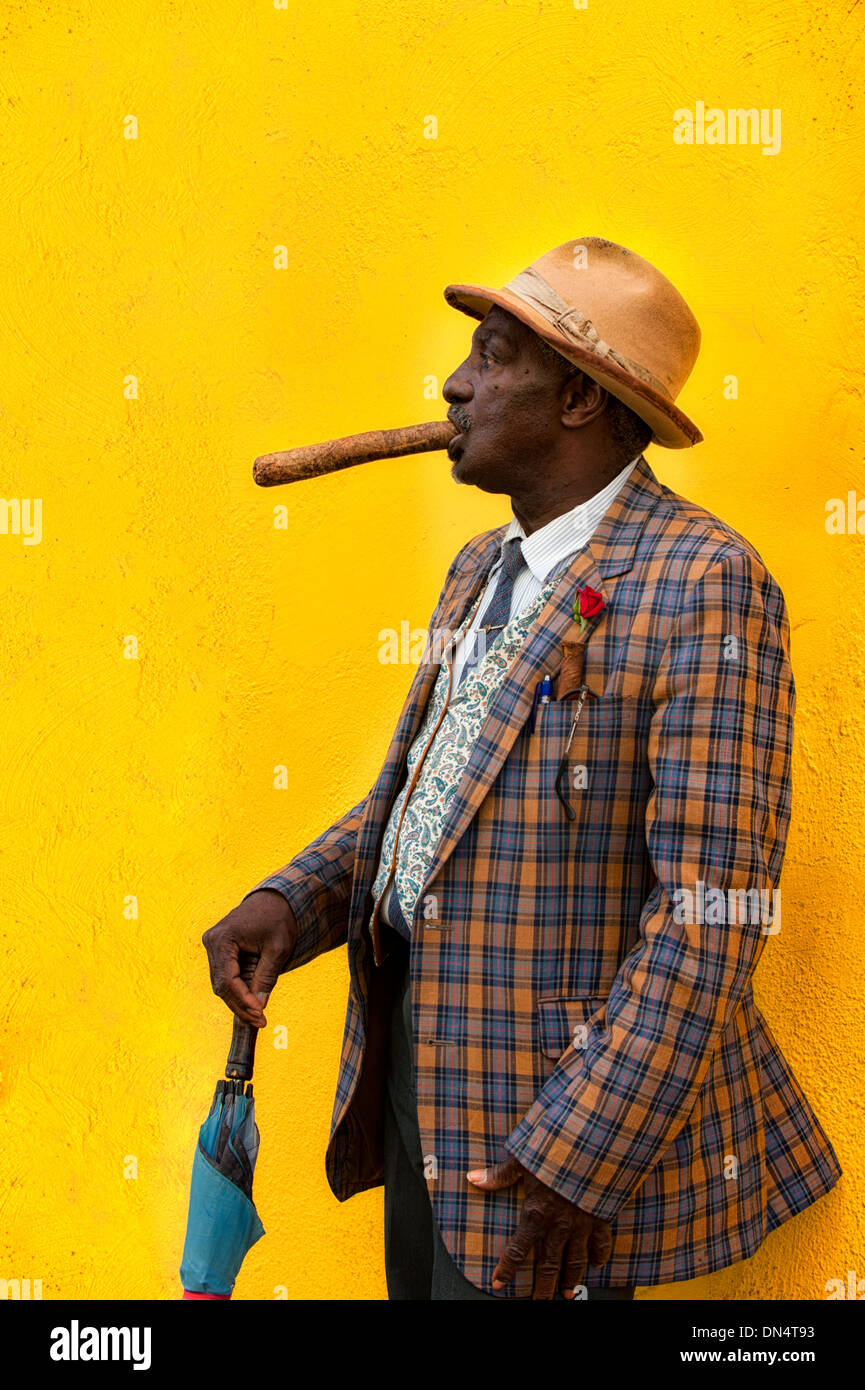 Profile man of color black smiling holds cigar in hand umbrella plaid jacket traditional dress in Havana Cuba street tourism Stock Photo